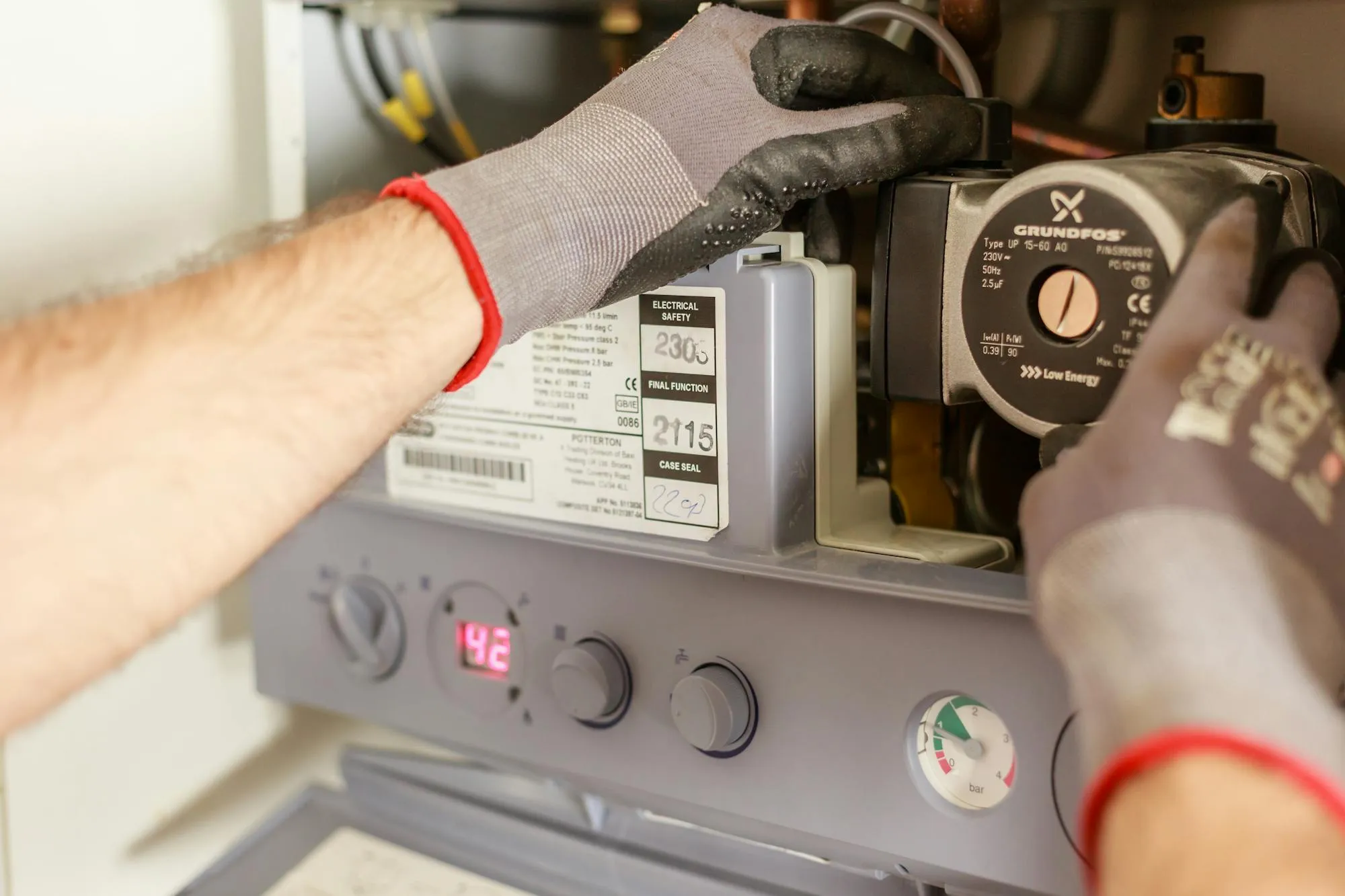Gloved engineer servicing a Potterton combi boiler in a Leicester home